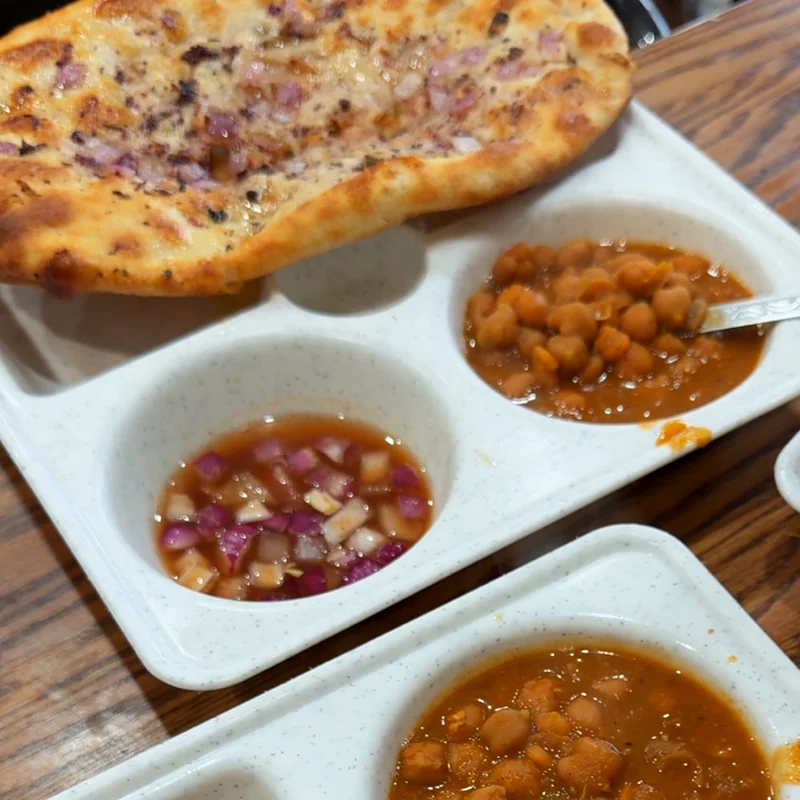 Amritsari kulcha on a tray with chickpea curry and chopped onion